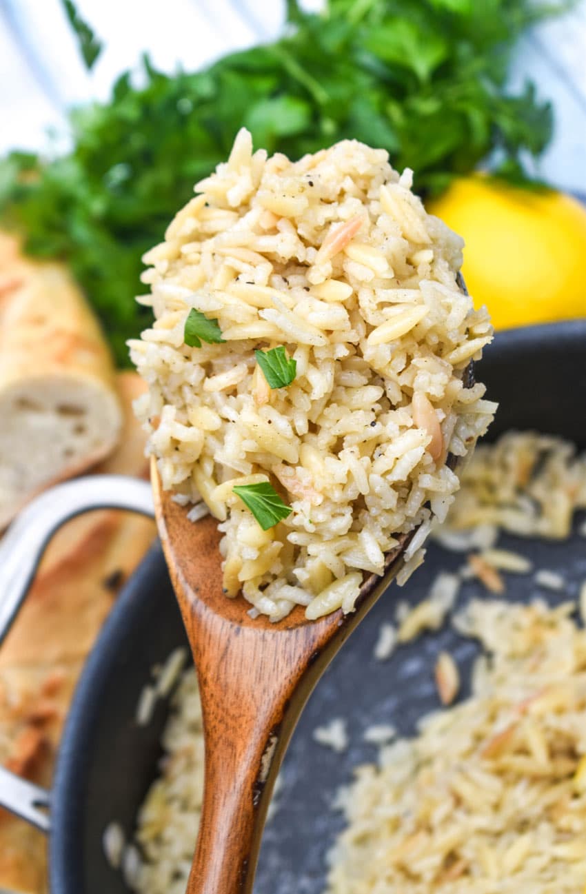 a wooden spoon holding up a scoop of lemon rice