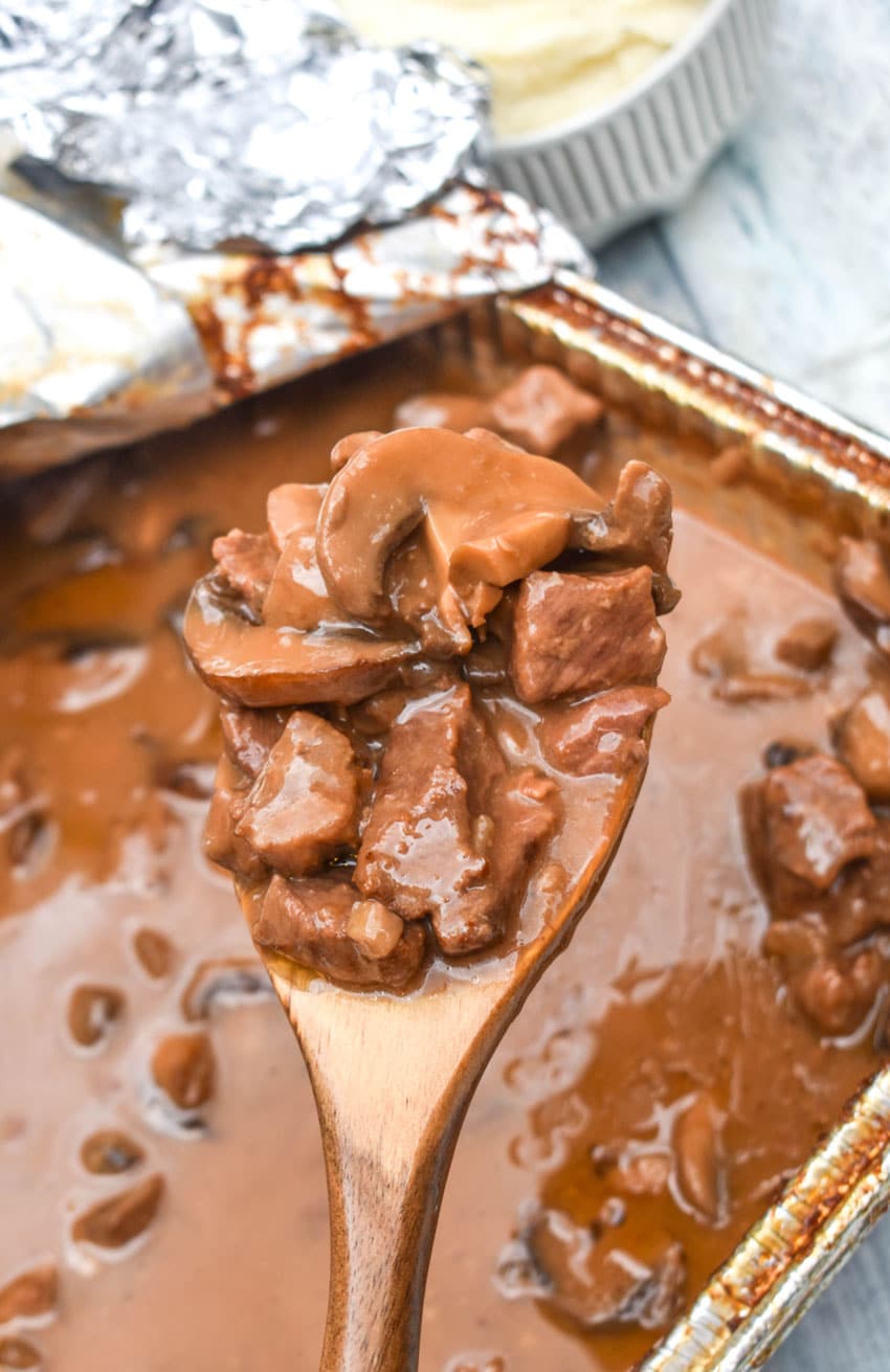 a wooden spoon holding up a scoop of no peek beef tips