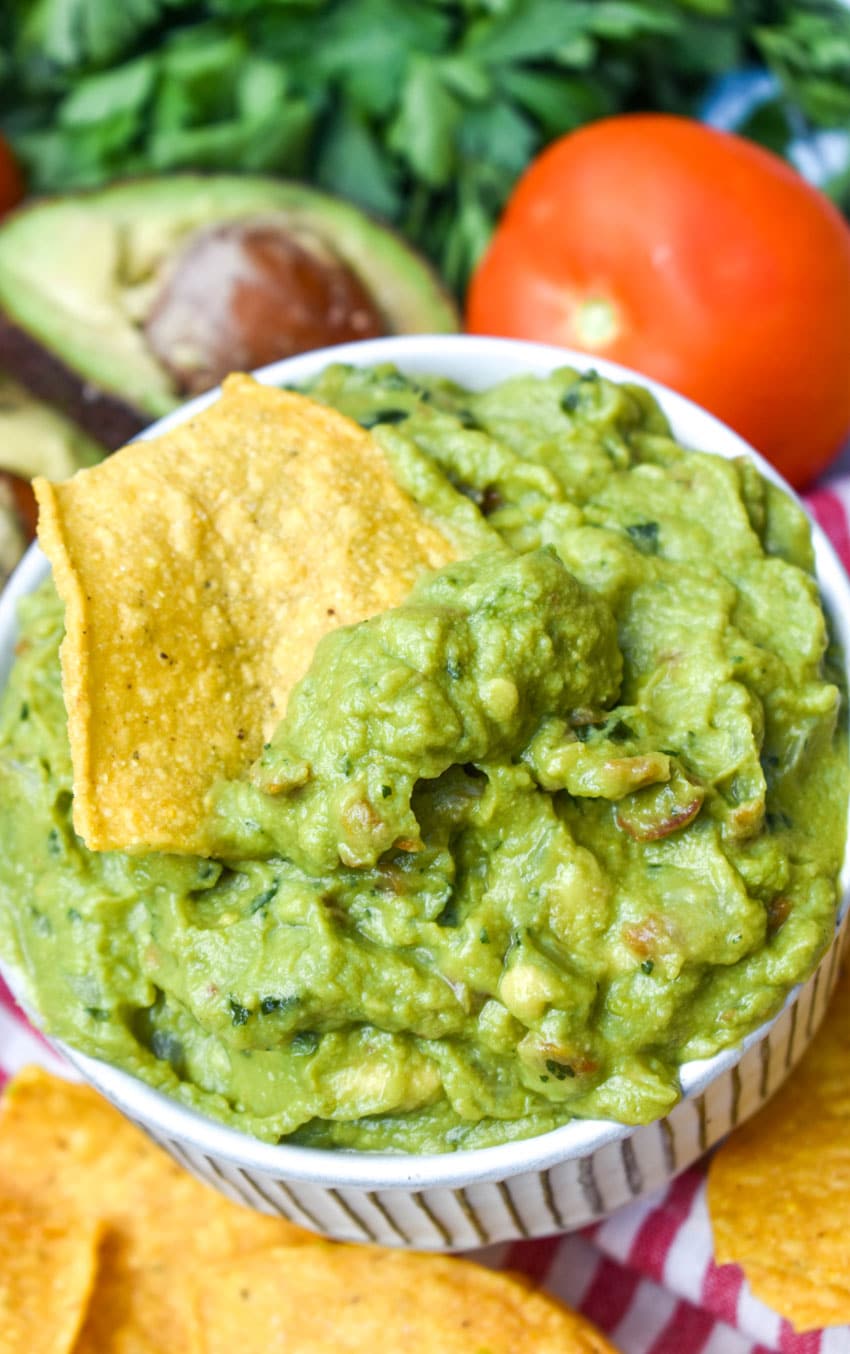the best homemade guacamole in a white bowl surrounded by tortilla chips