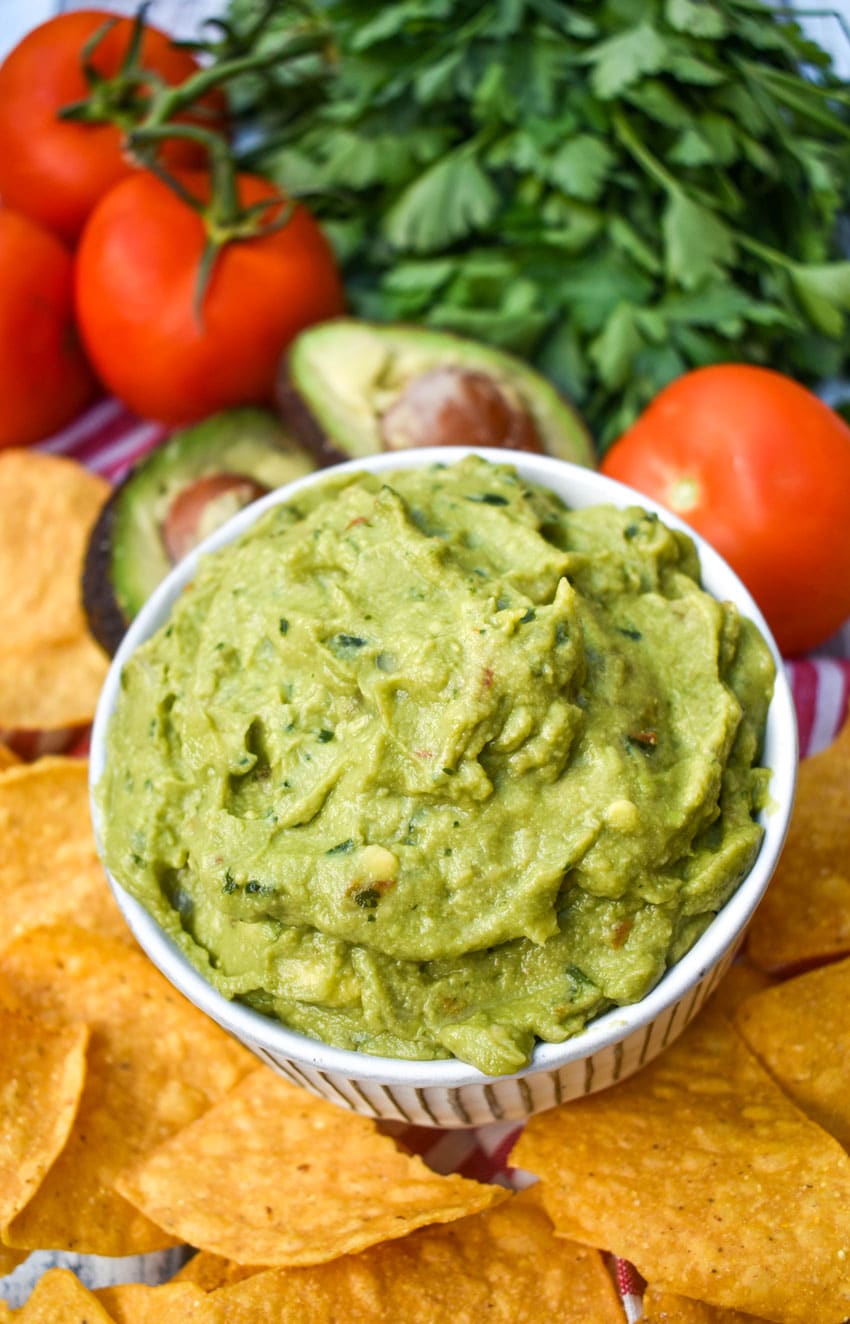 the best homemade guacamole in a white bowl surrounded by tortilla chips
