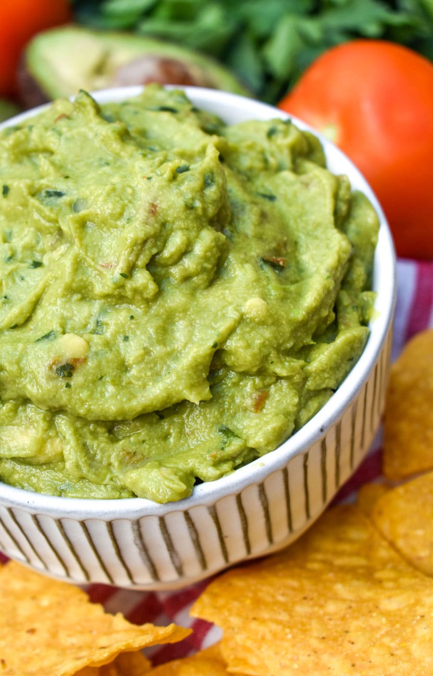 the best homemade guacamole in a white bowl surrounded by tortilla chips