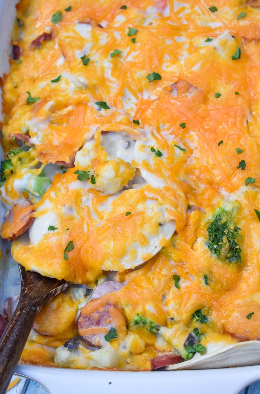 a wooden spatula scooping dump and bake pierogi casserole in a large white baking dish