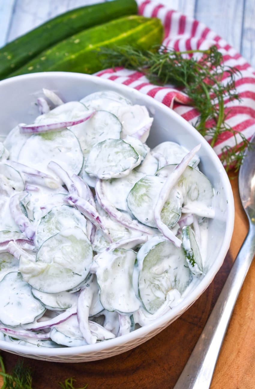 creamy cucumber salad in a white serving bowl