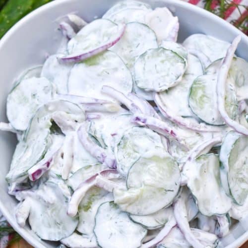 creamy cucumber salad in a white serving bowl