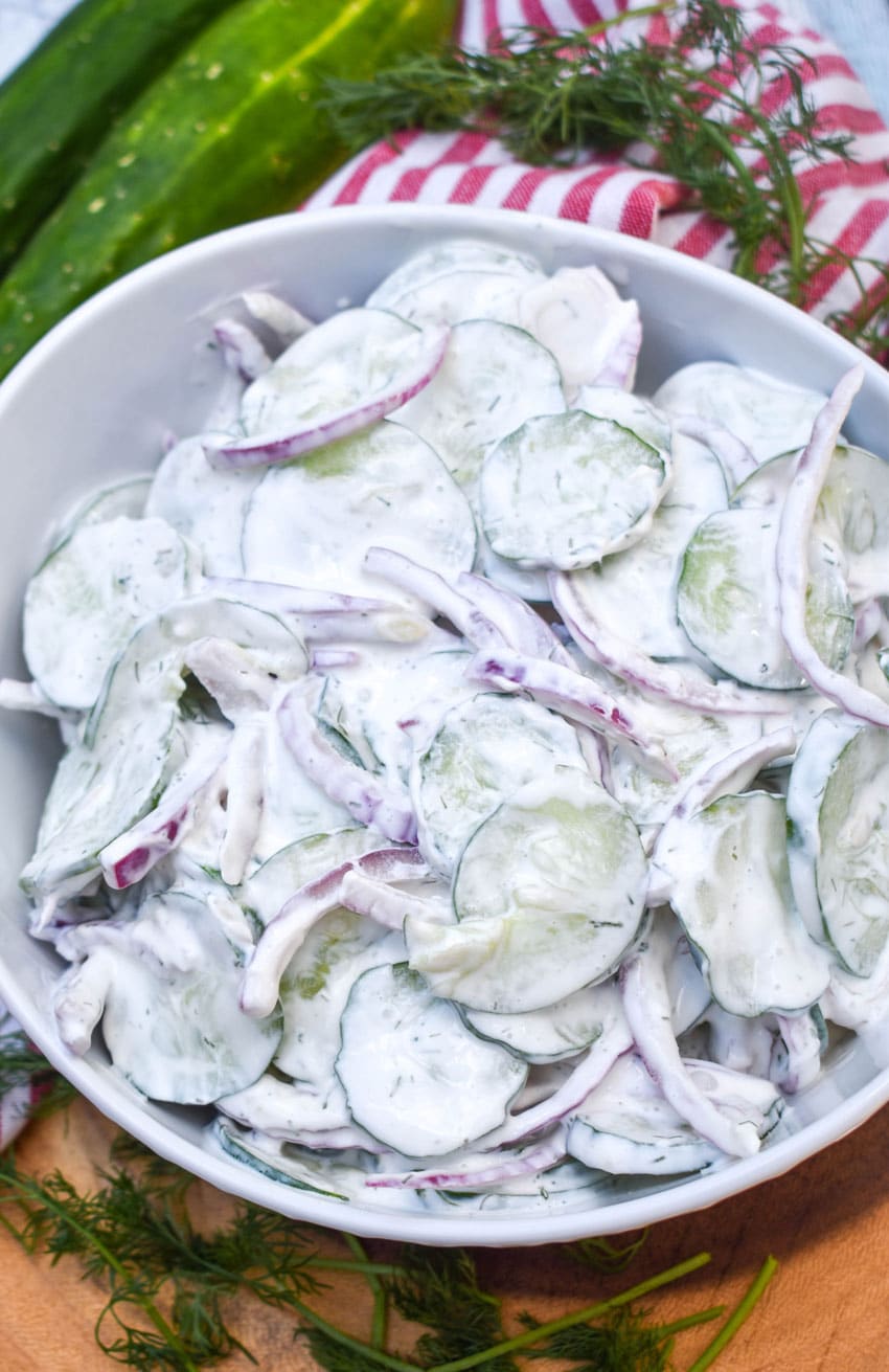 creamy cucumber salad in a white serving bowl