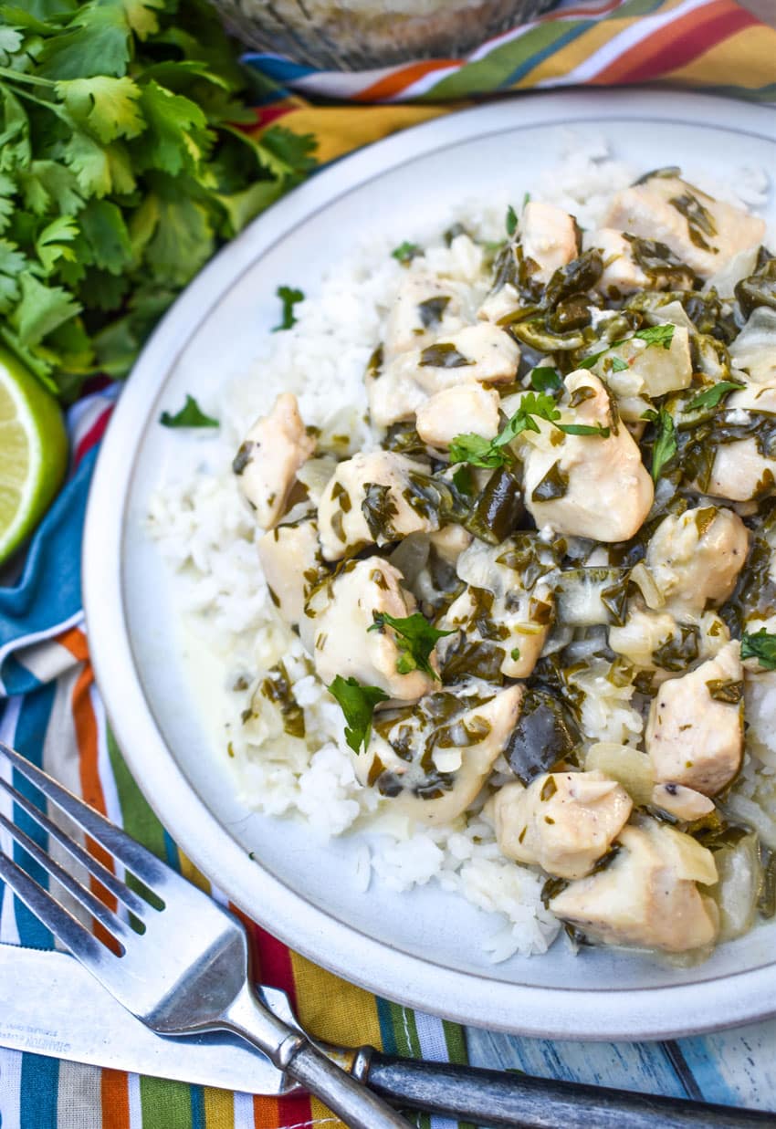 CREAMY POBLANO CHICKEN OVER STEAMED WHITE RICE ON A WHITE PLATE