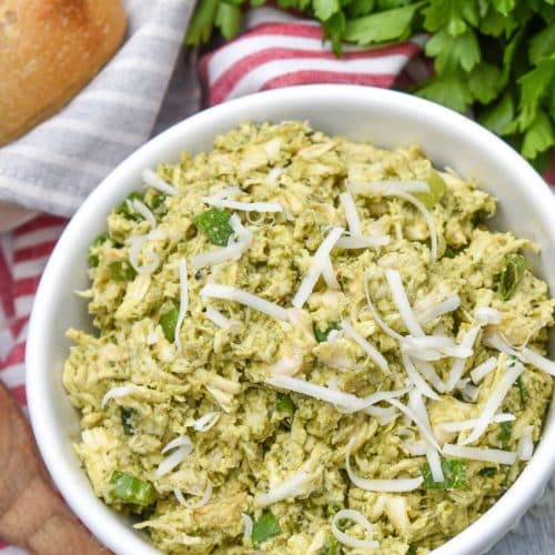 pesto chicken salad topped with shredded parmesan cheese in a white bowl
