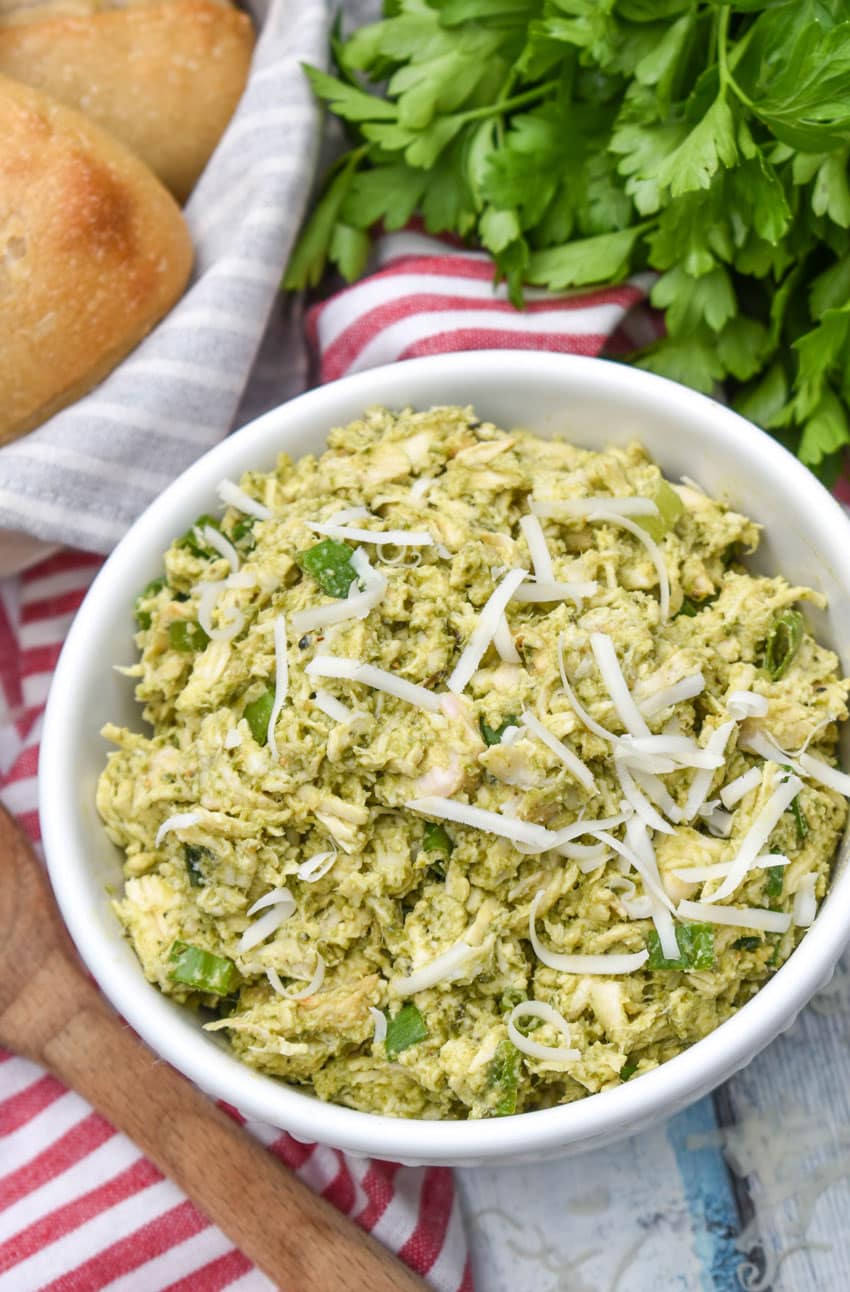 pesto chicken salad topped with shredded parmesan cheese in a white bowl