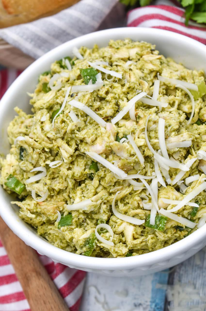 pesto chicken salad topped with shredded parmesan cheese in a white bowl