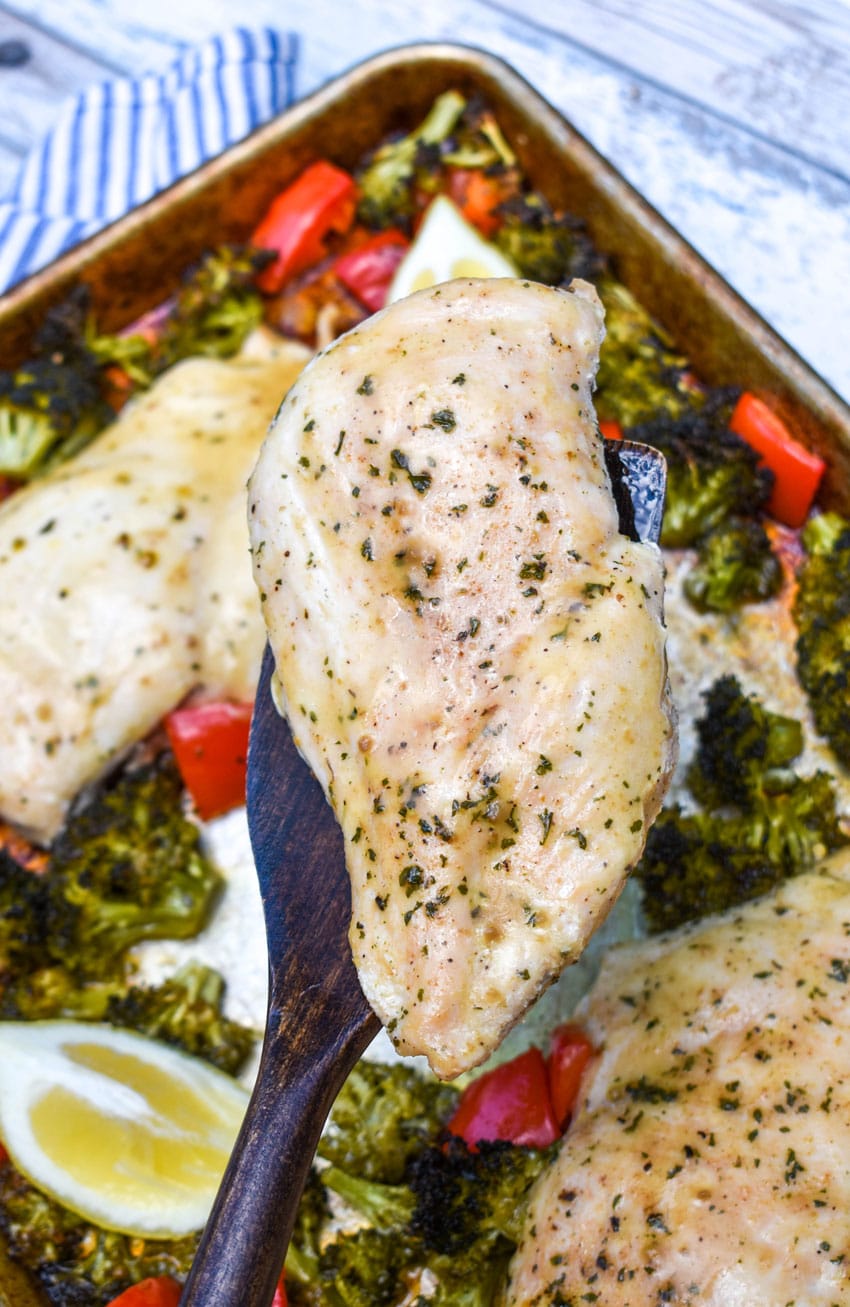 a wooden spatula holding up a piece of sheet pan lemon chicken