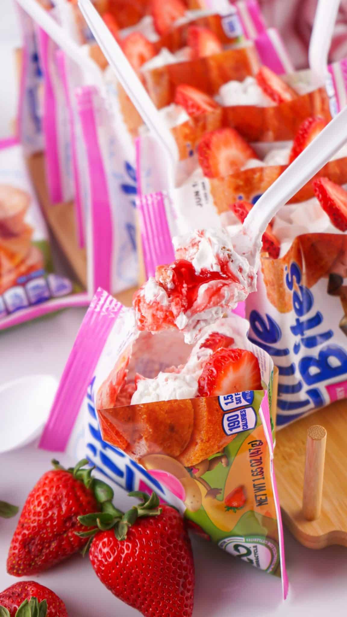 a white plastic spoon lifting up a scoop of a strawberry shortcake walking dessert