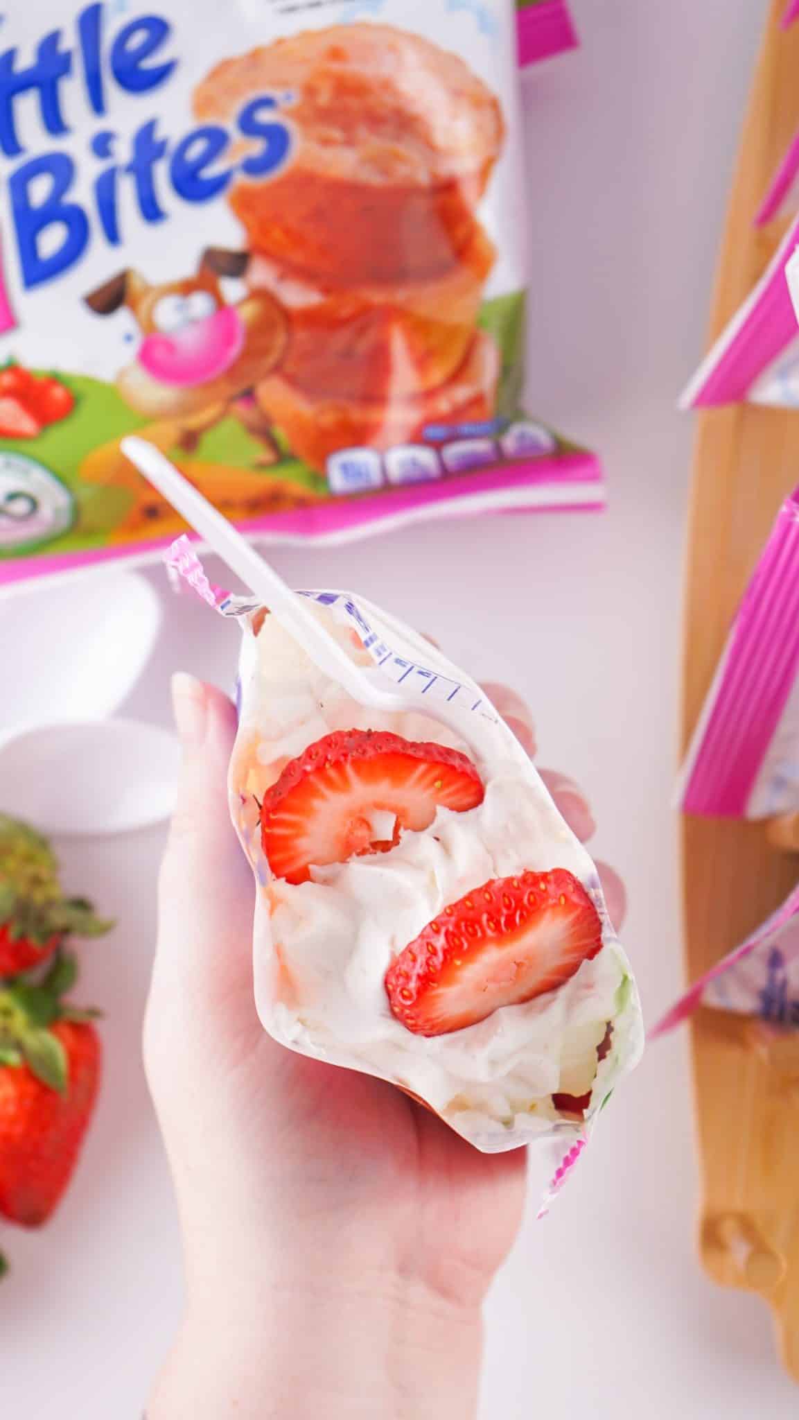 a hand holding up an open walking strawberry shortcake dessert