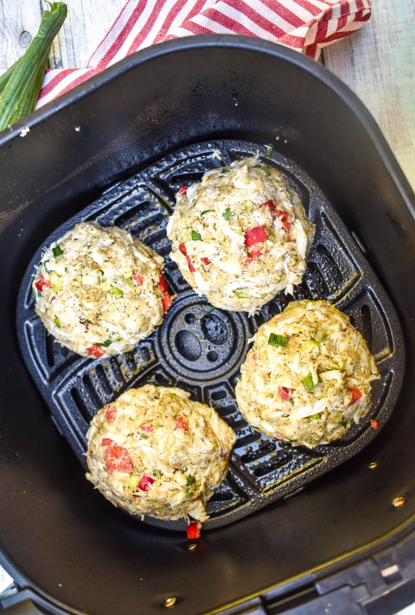 four fresh crab cakes in the basket of an air fryer