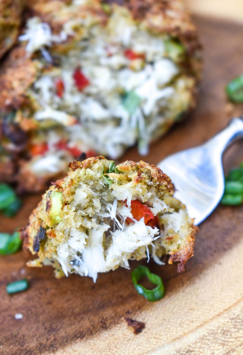 a silver fork lifting a scoop of air fryer crab cake off a wooden cutting board
