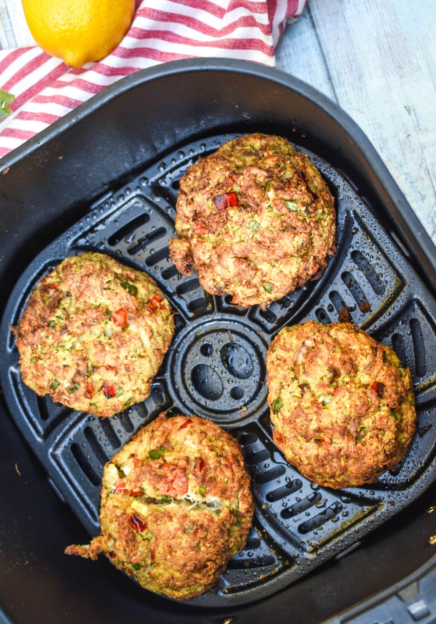 freshly fried crab cakes in the basket of an air fryer
