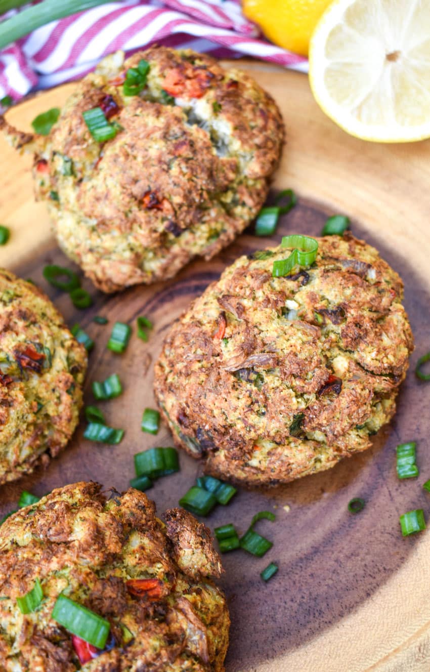 air fryer crab cakes topped with sliced green onions on a wooden cutting board