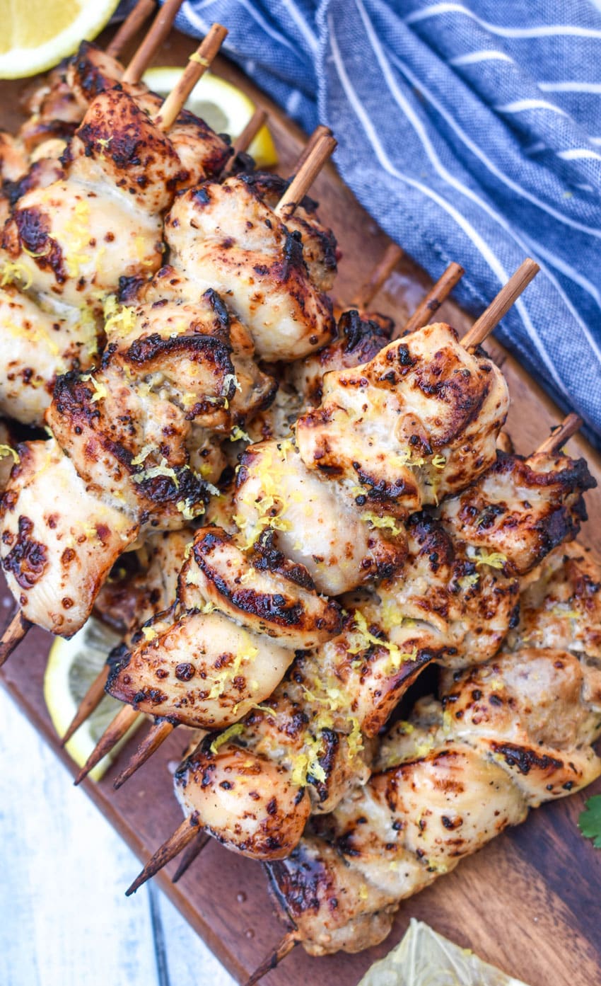 air fryer lemon chicken skewers topped with grated lemon zest piled on a wooden cutting board