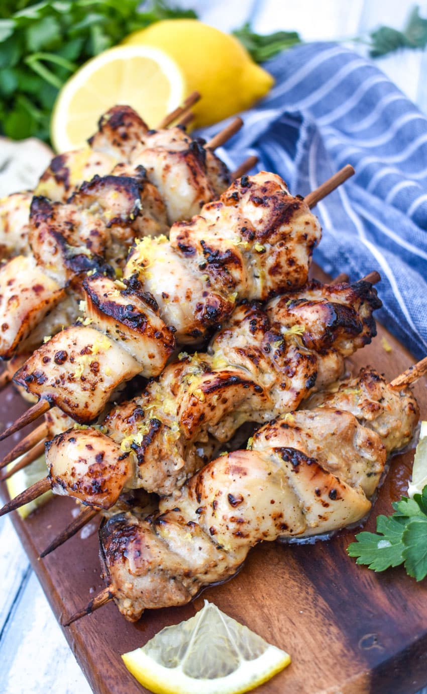 air fryer lemon chicken skewers topped with grated lemon zest piled on a wooden cutting board