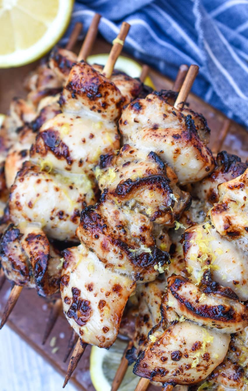 air fryer lemon chicken skewers topped with grated lemon zest piled on a wooden cutting board