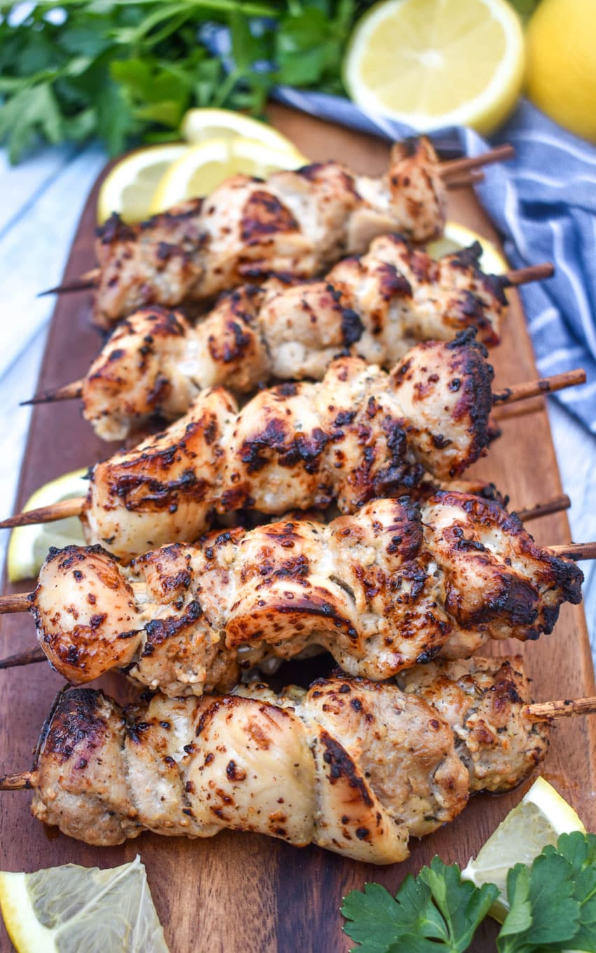 air fryer lemon chicken skewers topped with grated lemon zest piled on a wooden cutting board
