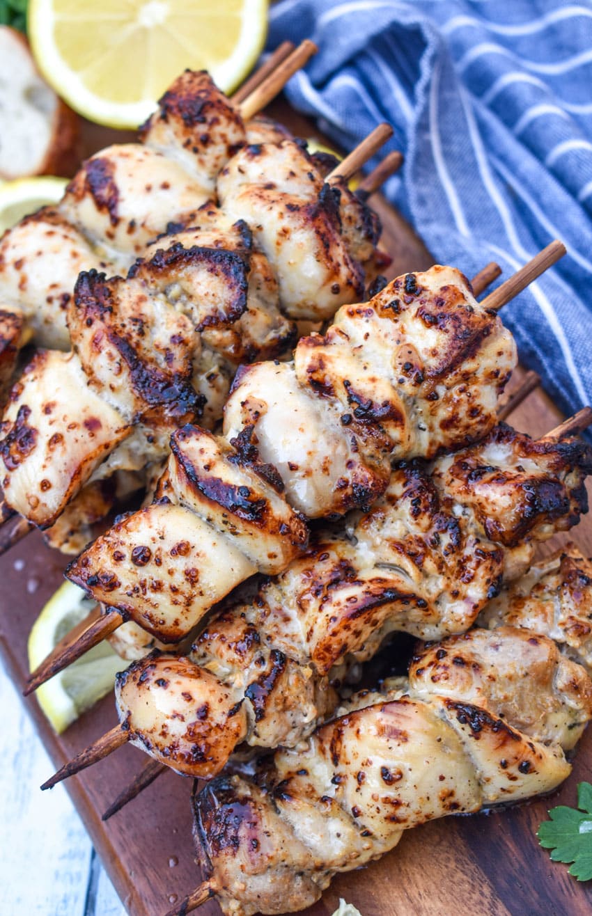air fryer lemon chicken skewers topped with grated lemon zest piled on a wooden cutting board
