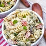 creamy caesar pesto pasta salad in two white ramekins with wooden spoons on the side