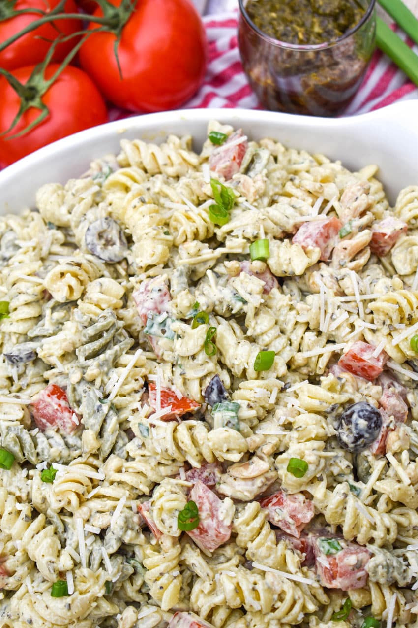 creamy caesar pesto pasta salad in a large white serving bowl