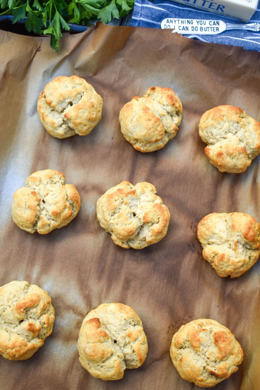 baked easy drop biscuits arranged in three rows on a parchment paper lined baking sheet
