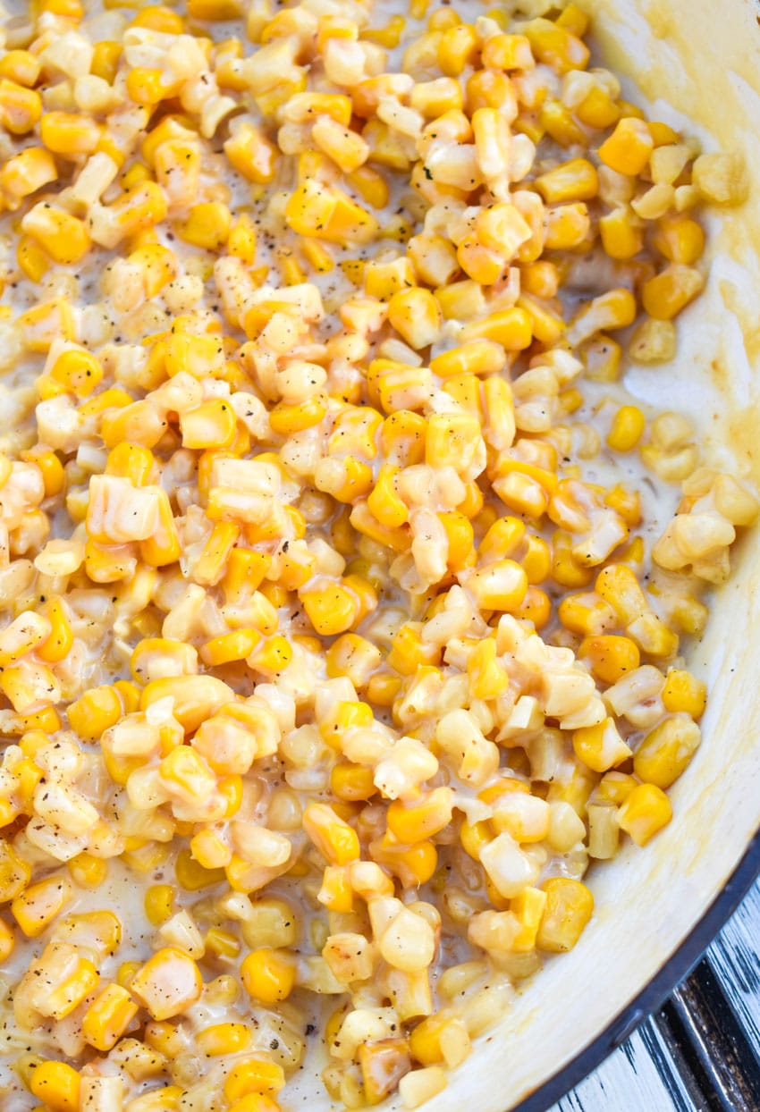 a close up of creamy honey butter skillet corn in a cast iron skillet