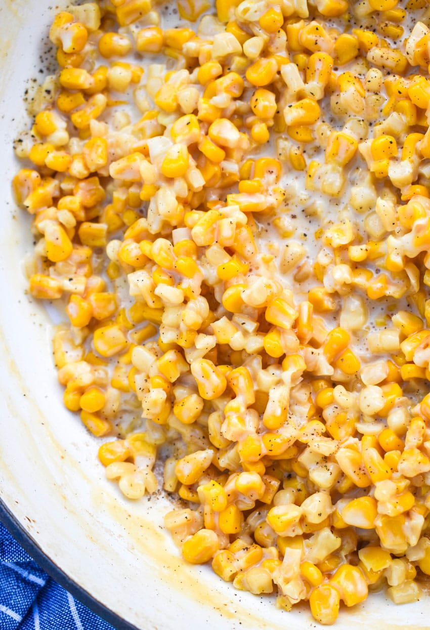a close up of creamy honey butter skillet corn in a cast iron skillet