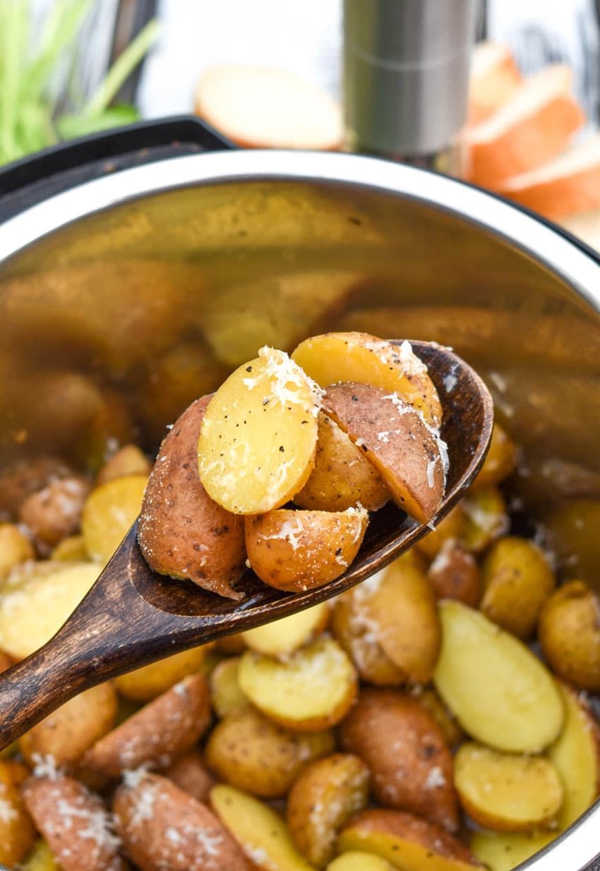 a wooden spoon holding up a scoop of instant pot italian potatoes