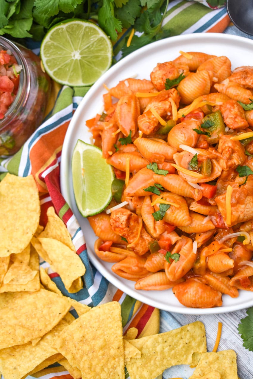 one pot chicken fajita pasta on a white dinner plate with a lime wedge on the side