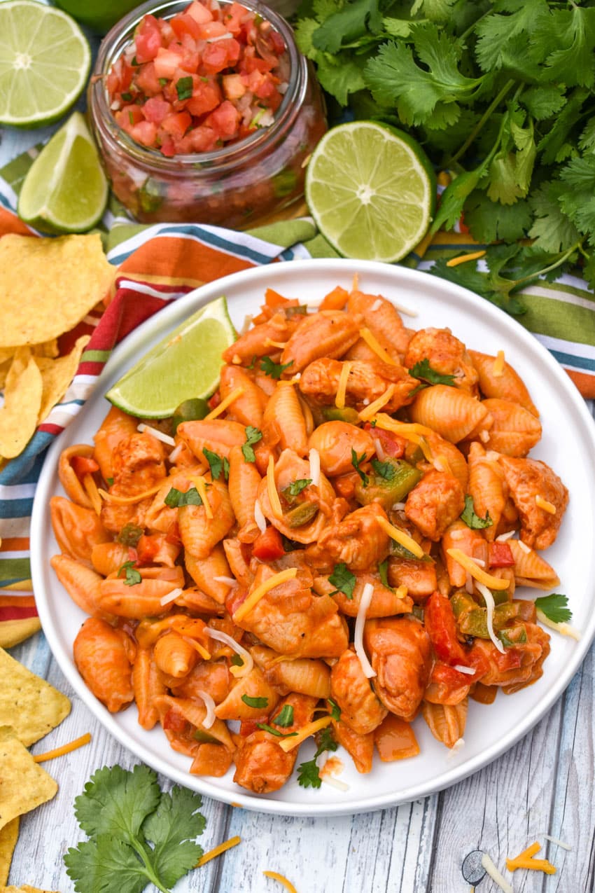 one pot chicken fajita pasta on a white dinner plate with a lime wedge on the side