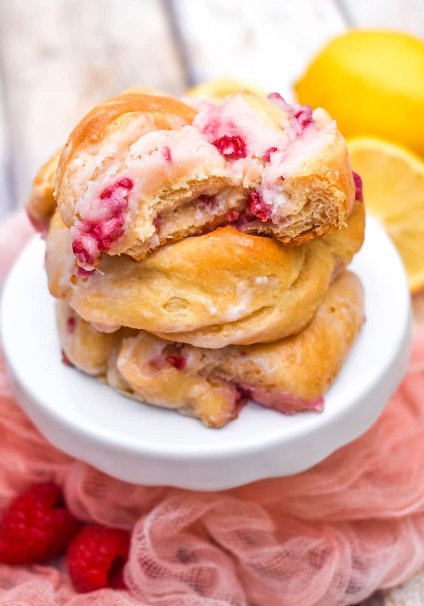 a stack of three raspberry lemon danishes on a small white cake stand