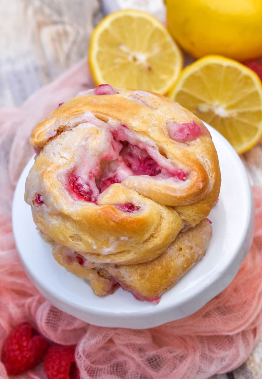 a stack of three raspberry lemon danishes on a small white cake stand