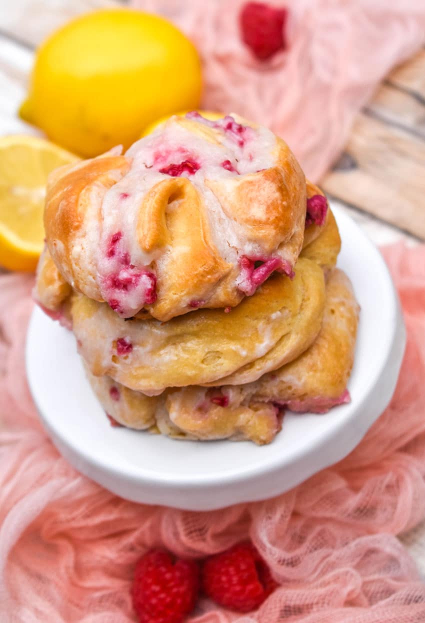 a stack of three raspberry lemon danishes on a small white cake stand