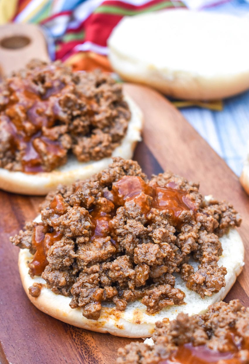 taco seasoned ground beef topped with taco bell mild taco sauce on two white buns on a wooden cutting board