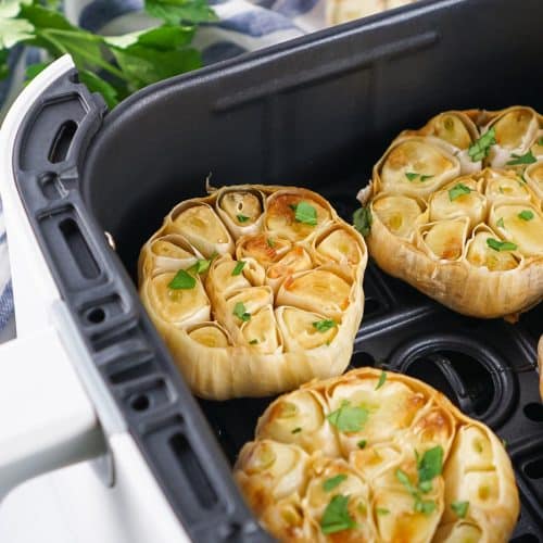 roasted garlic cloves in the basket of an air fryer