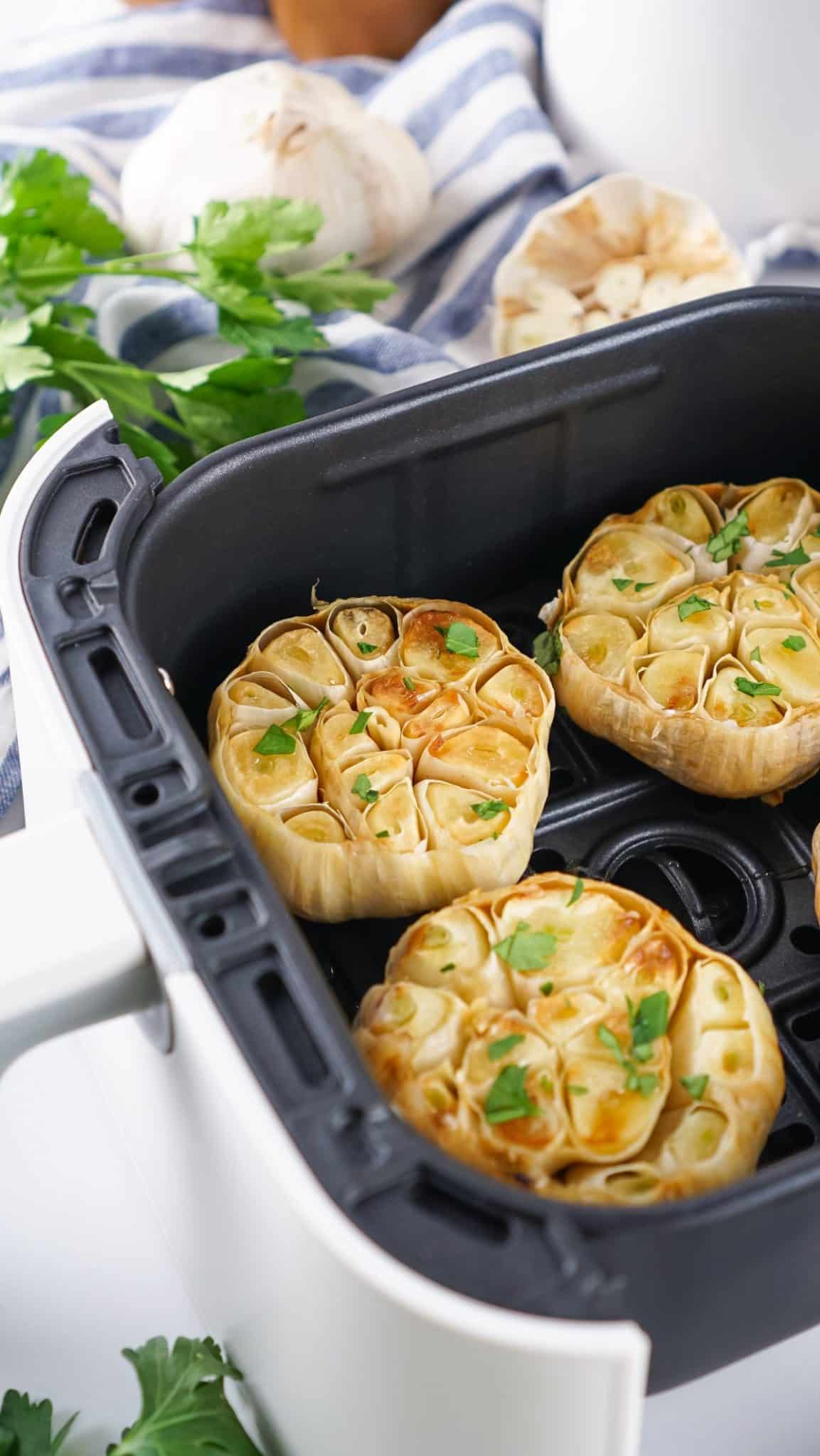 Easy Roasted Garlic (Air Fryer Recipe) roasted garlic cloves in the basket of an air fryer