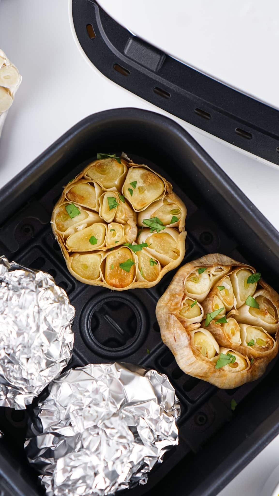 roasted garlic cloves in the basket of an air fryer