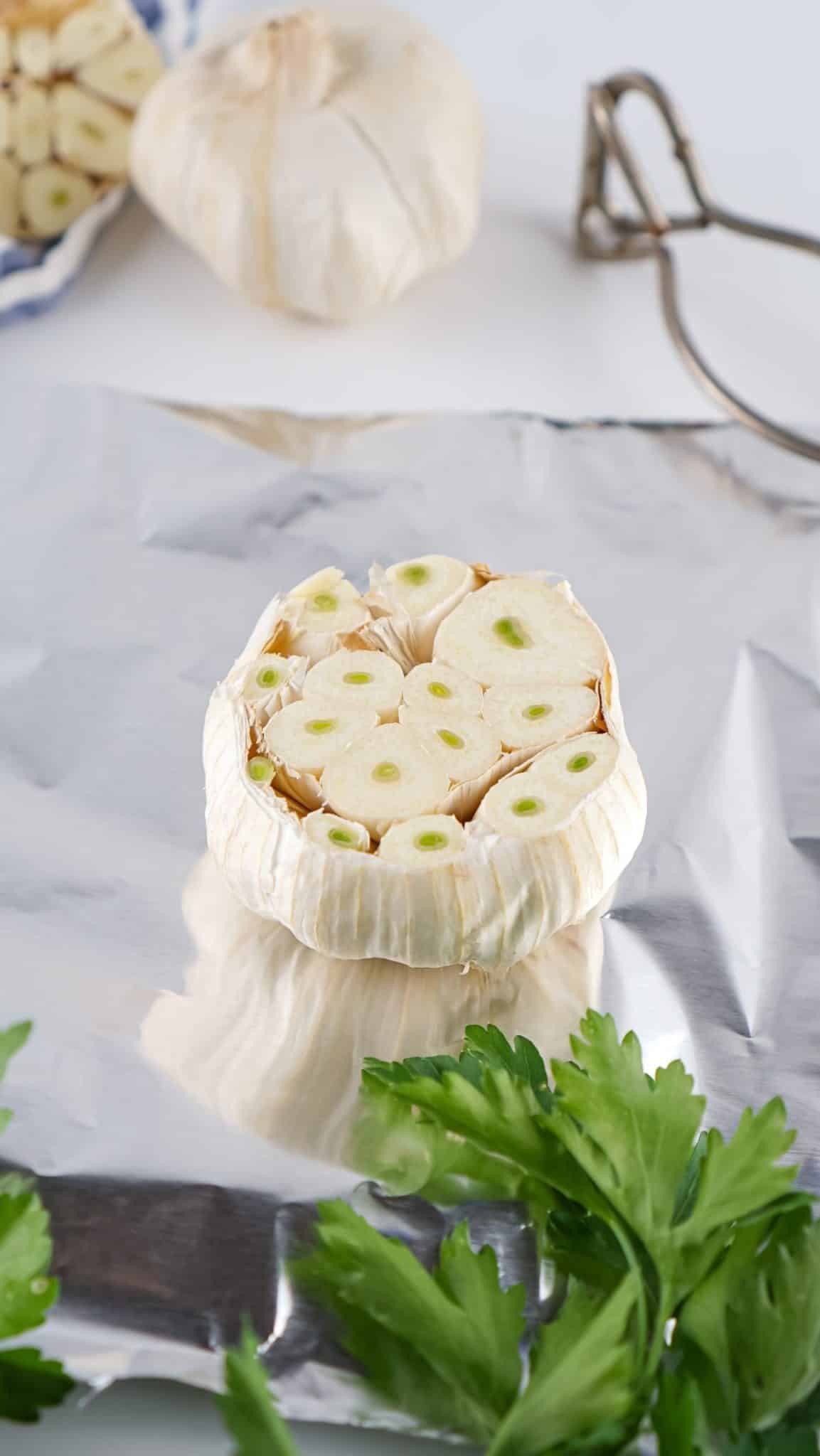 a garlic bulb cut in half and resting on a sheet of aluminum foil