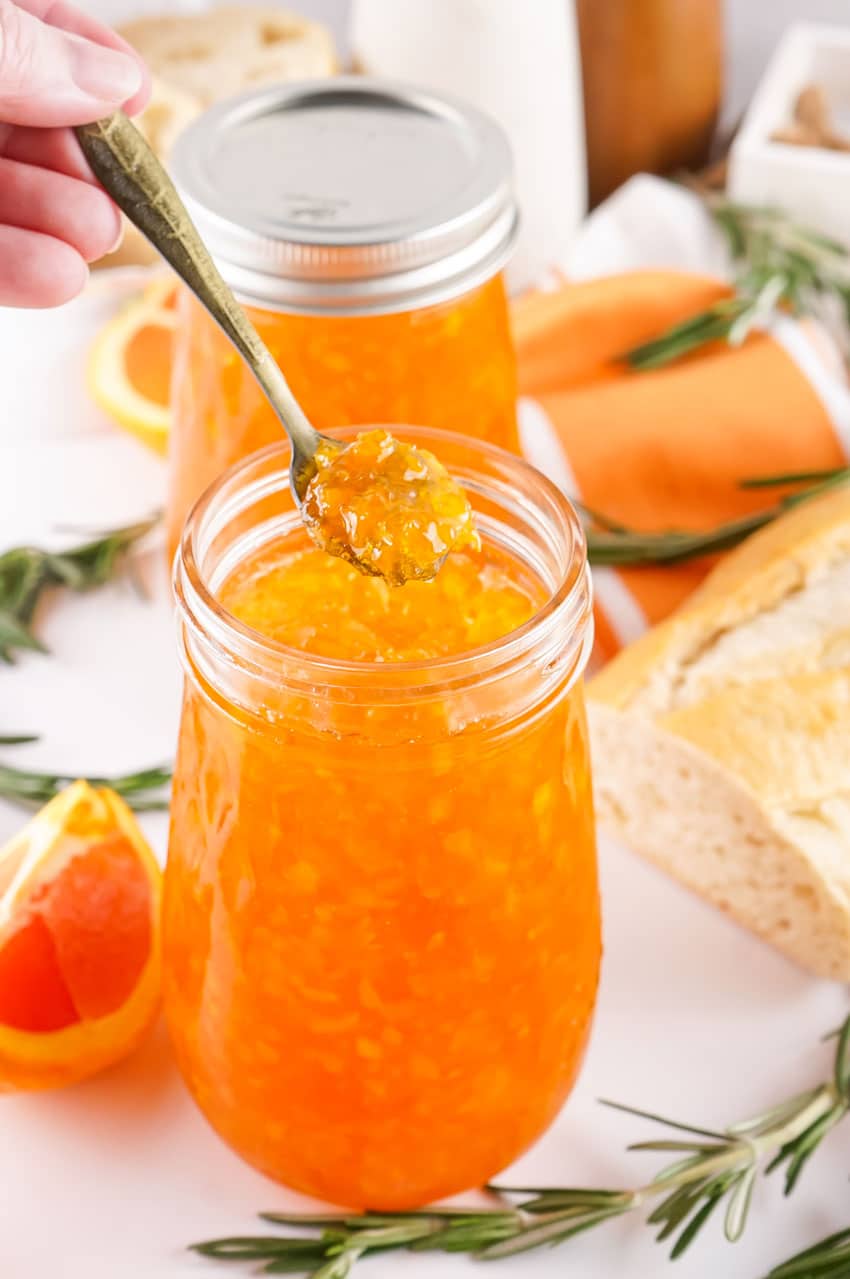 a small silver spoon holding up a scoop of homemade orange marmalade