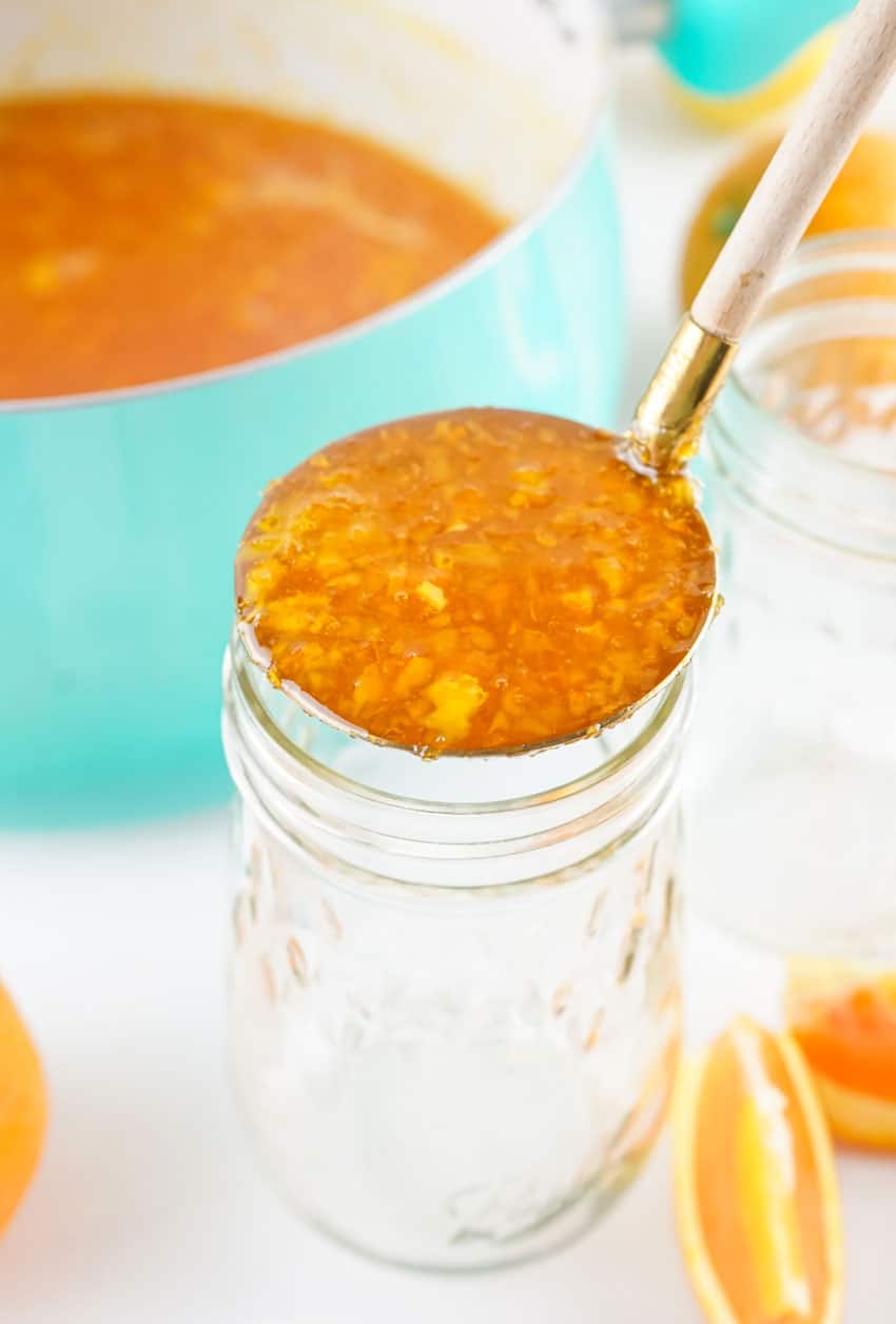 a silver ladle holding up a scoop of homemade marmalade made with no pectin