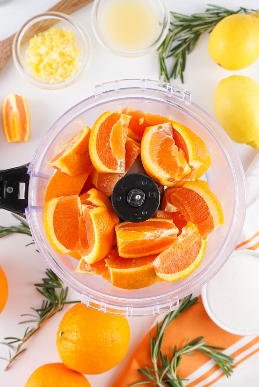 cut oranges in the bowl of a food procesor