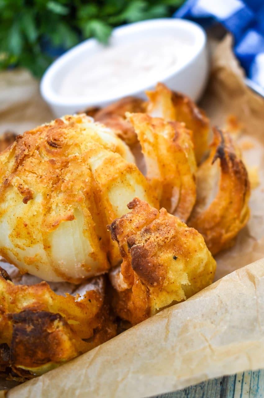 air fryer bloomin' onion on a brown parchment paper lined tray
