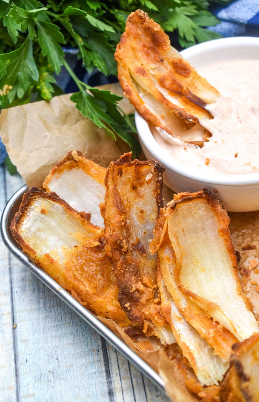 a close up of fried onion petals resting on a brown parchment paper lined food tray