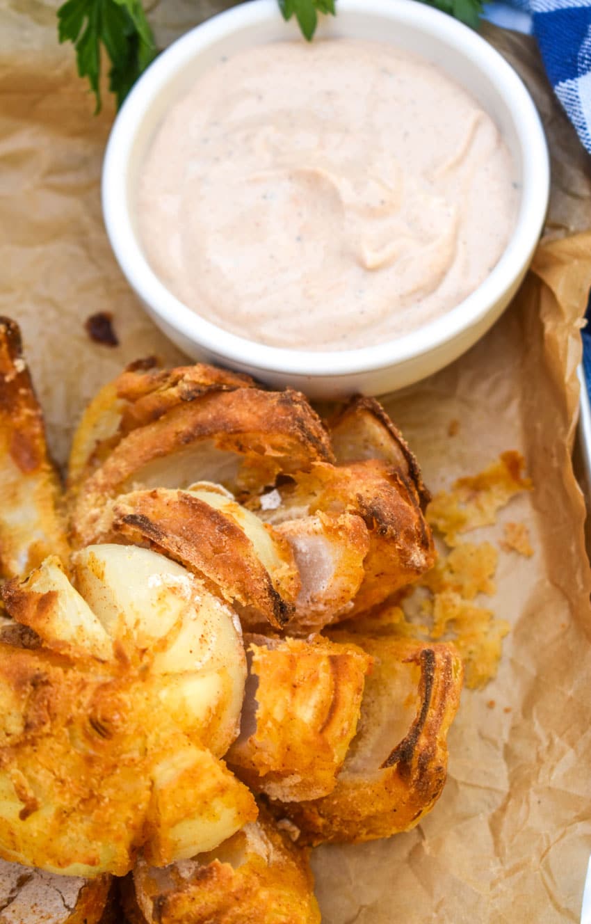 air fryer bloomin' onion on a brown parchment paper lined tray