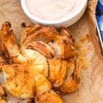 air fryer bloomin' onion on a brown parchment paper lined tray
