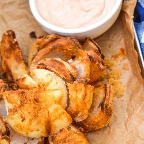 air fryer bloomin' onion on a brown parchment paper lined tray