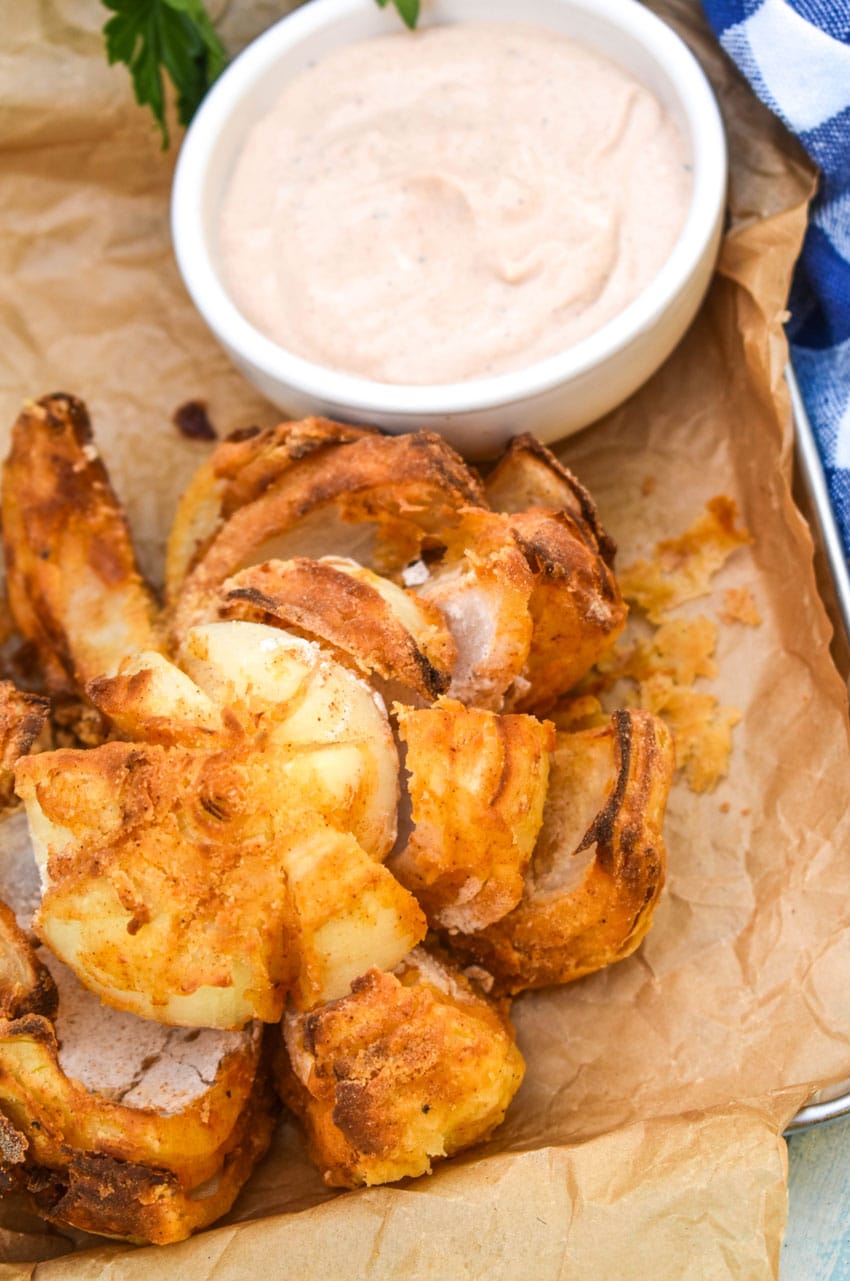 air fryer bloomin' onion on a brown parchment paper lined tray